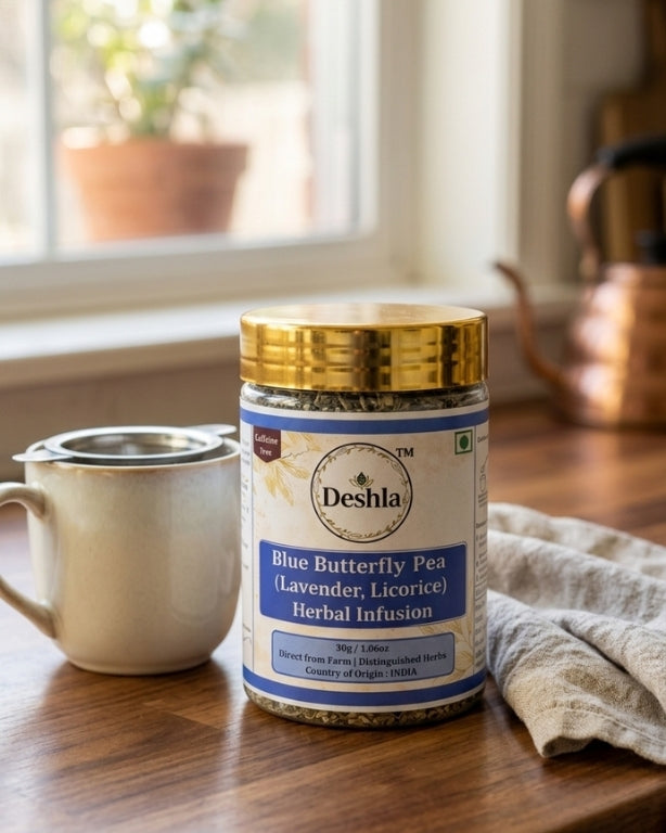 Deshla Blue Butterfly Pea Herbal Infusion jar on a wooden table with a cup and towel in the background.