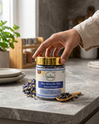 Hand opening a jar of Deshia Blue Butterfly Pea Dried Flower on a kitchen counter.