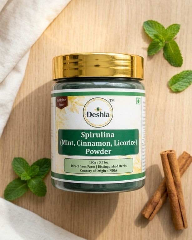 Deshla Spirulina powder jar with mint leaves and cinnamon sticks on a wooden surface
