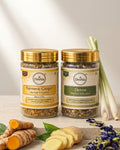 Two jars of Deshla herbal infusions with turmeric and ginger on a wooden surface.