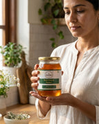 Woman holding a jar of Dabur Raw Forest Honey in a kitchen setting